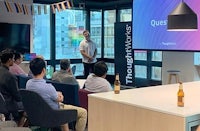 a group of people sitting at a table watching a presentation