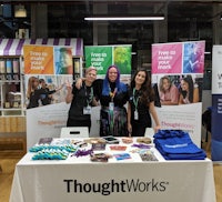 three women standing in front of a table with a thoughtworks banner